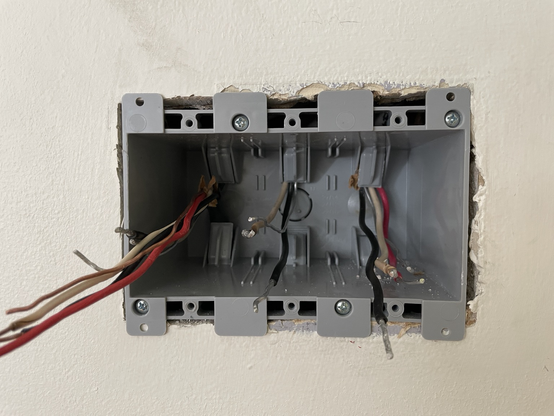 A new ‘old work’ box installed in a sheet rock wall with wires pulled through as much as able given the available slack