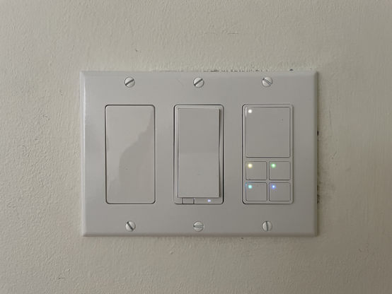 A 3 gang light switch with a smart decora style rocker in the center, and a 5 button keypad on the right. The left is filled in with a blank.