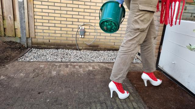 Jongedame op hoge witte hakken kijkt tevreden terug op een dagje klussen ter voorbereiding van warmtepomp plaatsing.