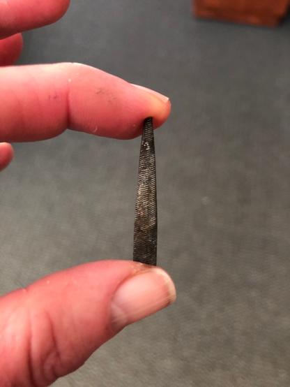 about one and one half inches of the end of a metal file held between the thumb and forefingers of a hand