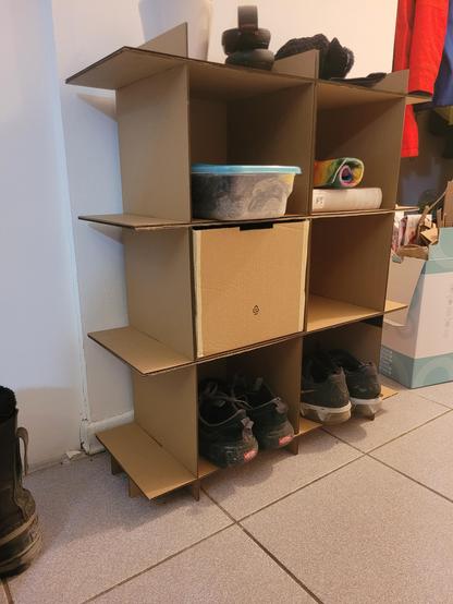 Shelf in use: it can hold shoes, books, tools, a drawer made out of cardboard, and things to put in your pockets before you leave the house.