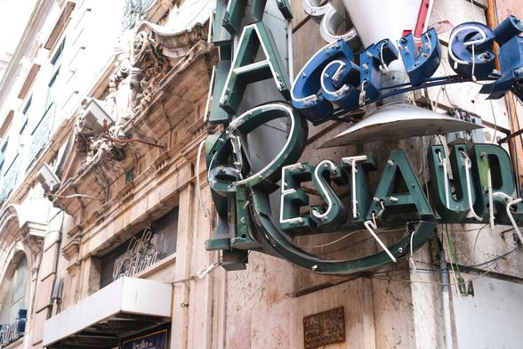 Picture of the neon sign of a long closed restaurant, which is slowly falling apart.
