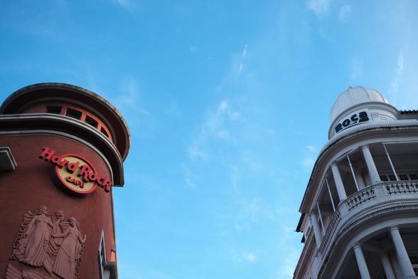 Photo of the top of the Hard Rock Cafe on the left and the Roca Gallery on the right in front of the blue sky.