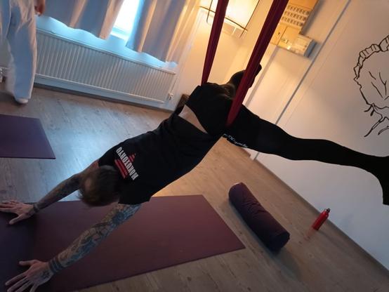 Harrastaja roikkuu joogaliinassa lantioroikunnassa, kädet lattiassa työntäen kroppaa taaksepäin suoraksi.