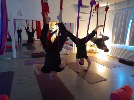 Harrastajat roikkuvat pää alaspäin joogaliinoissa eri vaiheissa liikesarjaa.