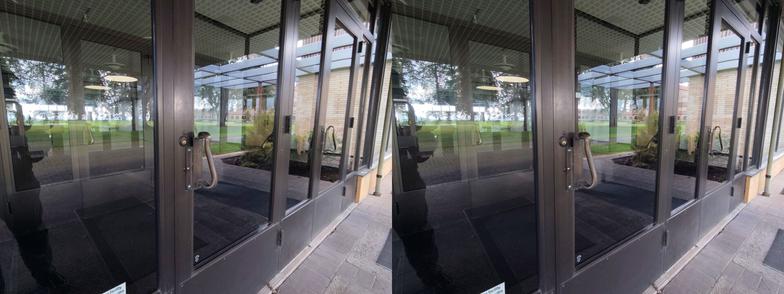 Stereoscopic, side-by-side view. Exterior of the entrance of the Mt. Angel Abbey library. We are looking at the glass doors. There is an undulating brass handle on each door.