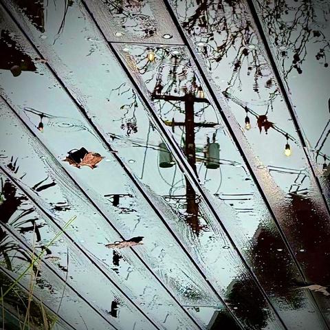 Reflection of a power line/pole on a wet deck. The image has been flipped by 180 degrees so the pole is right side up.