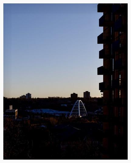 The walterdale bridge in Edmonton, glowing from sunset light just before the sun is fully blocked.  Frames by apartment balconies on the right.
