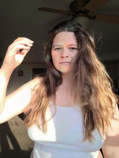 A woman looks at the camera, she looks a little overwhelmed by her long hair.