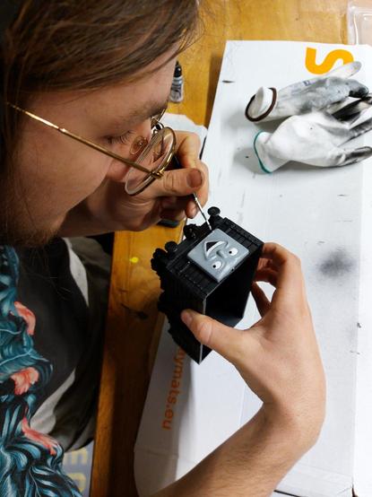 Dude painting a Thomas the steam engine wagon with a very manically happy face. And that's the wagon and not the student!
