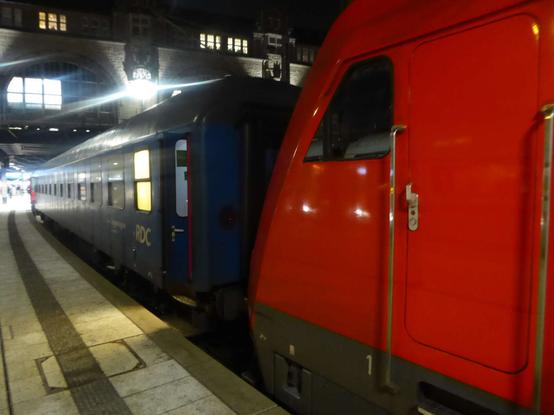 Red RDC locomotive pulling an SJ-branded RDC wagon in Hamburg Hbf