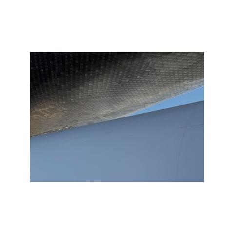 black tiled belly of space shuttle above the light blue skin of the top of a 747 with sliver of blue sky between them