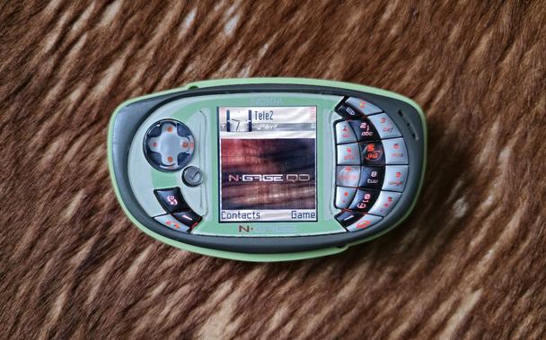 Green Nokia N-Gage QD (RH-29) mobile phone / hand-held gaming console with keys backlit in red and screen showing a desktop with N-Gage QD stylized wallpaper