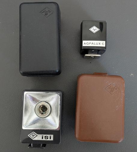 Fotoblitz "Agfa Agfalux C" mit brauner Plastikbox und Fotoblitz "Agfa isi" mit schwarzer Plastikbox