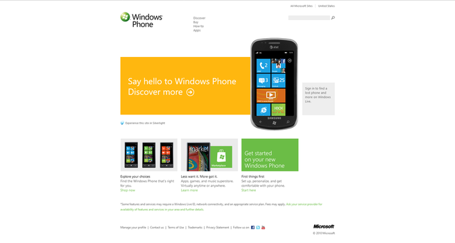 **Alt Text**: Screenshot of the Windows Phone website as it appeared on October 31, 2010. The page prominently features a Windows Phone with the AT&T logo and various app tiles on the screen. The main section has a large orange banner with the text "Say hello to Windows Phone. Discover more" and a right arrow. Below this banner, there are three sections with images of different Windows Phones and text descriptions
