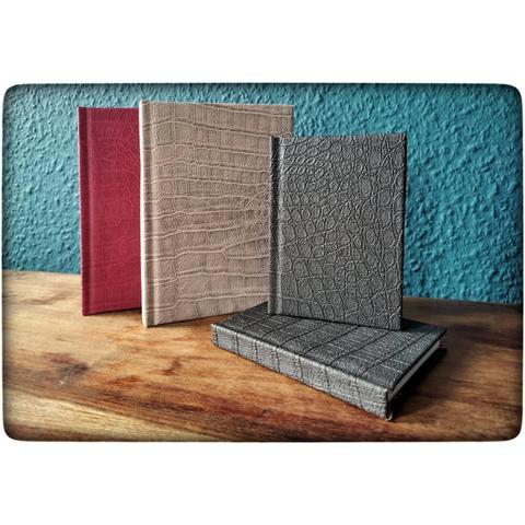 Drei Bücher, in verschiedenen Größen, stehen auf einem Tisch. Ein viertes liegt. Von links nach rechts: pinkes Krokodil// rosa/gold Krokodil// schwarzes Krokodil.