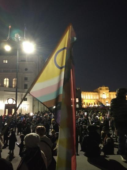 Pride flag, a large group of people, historical buildings including the Austrian national library