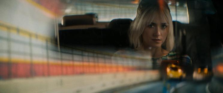 Dakota Johnson in the back of the car seen through the rearview mirror while driving through a tunnel with tiled walls