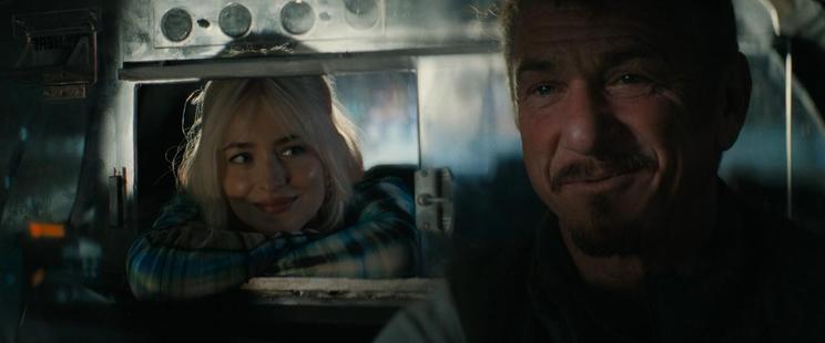 view into the cab from the windshield at night, Dakota Johnson is leaning into the opened window of the passenger seperator, smiling at Penn who's at the wheel talking amused
