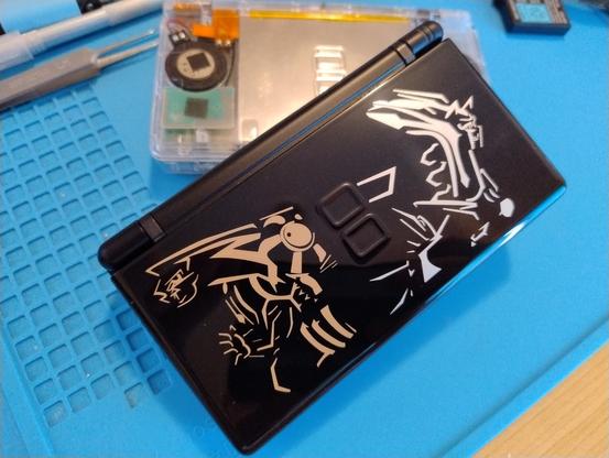 A black DS Lite with a Pokemon gold/silver themed top cover