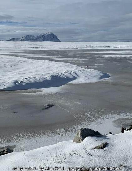 A landscape in winter. A frozen loch, with the mountain of Ben Hope beyond