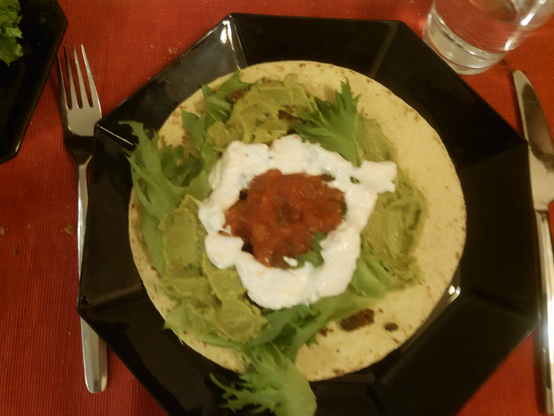 Lautasella on avonainen tortilla, jonka päällä on salaatinlehtiä ja guacamolea, niiden päällä valkoisena rinkinä hapankermaa ja keskellä punaista papusalsaa. Etäinen yhdennäköisyys runebergintortun hilloon ja kuorrutukseen.