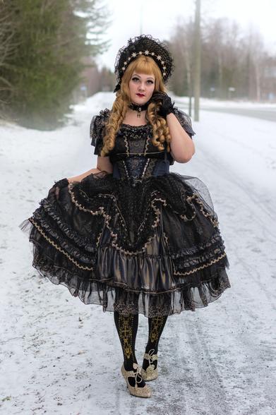 Model wearing black 'elegant gothic lolita' dress with gold detailing, including matching headdress.
