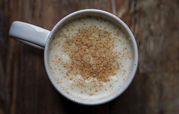 Top down view of a mug with a mint tea and nutmeg shavings.