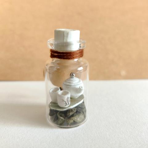 Miniaturka w małej butelce (10 ml). W srodku zestaw do herbaty wykonany z papieru. Czajniczek i dwie czarki.