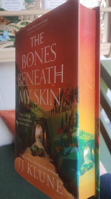 hardback of The Bones Beneath my Skin, the new TJ Klune novel, held at an angle to show both the cover and the spredges (painted page edges)