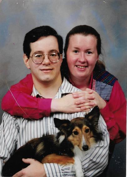 A professional family photo, when our family was only myself, my husband, and our new dog Tigger. 

I am behind my husband (much thinner than I am today), with my light brown hair pulled back and one arm around him, peaking over his shoulder. He is in the foreground, with dark hair and glasses, and he is holding Tigger (a small, mostly brown dog with lots of long fur) in his arms.