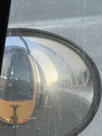 A reflected image of a yellow school bus in one of its big round mirrors.