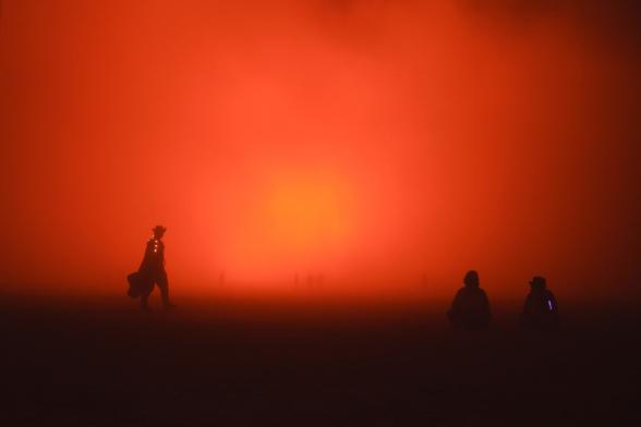 A Black Rock Ranger walks the burn perimeter during the Temple Burn at Burning Man 2024