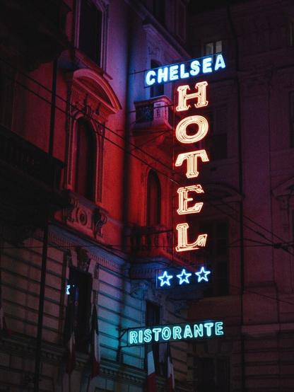 A picture of a colourful neon sign on a wall s saying "Hotel"
