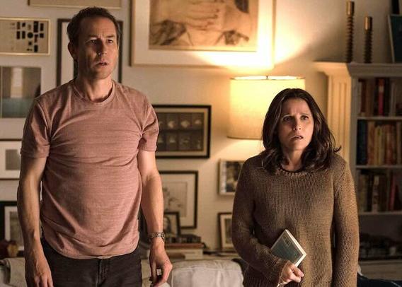 Tobias Menzies and Julia Louis-Dreyfus stand in their living room looking at someone with shocked expressions.