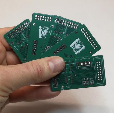 Une main gauche tient 5 PCB vert à la manière d'un jeu de cartes.