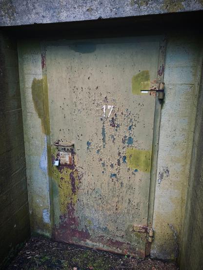 Door of bunker entrance. Paint chipping off and the number “17” marked on the door.