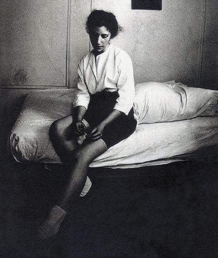 Das schwarz-weiß Foto zeigt Diane DiPrima mit kurzen Haaren auf einem Bett sitzend, den Blick auf ihre Hände gesenkt
Foto: Ausschnitt aus "Memoirs of a Beatnik by Diane DiPrima" (1998)