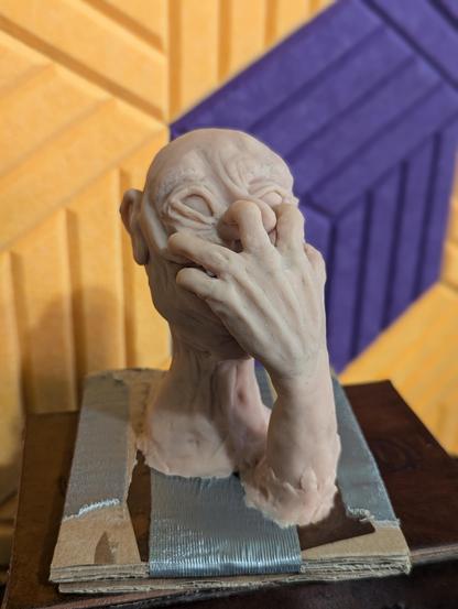 Eine Skulptur aus rosafarbenen Sculpey. Sie zeigt den Kopf eines älteren Mannes der sich mit seiner Hand in seinem Gesicht festkrallt.