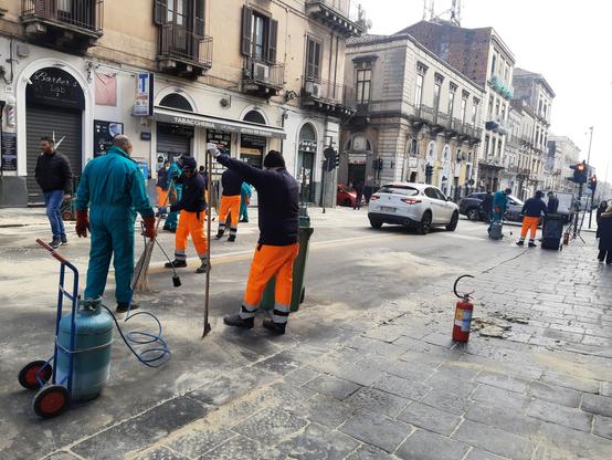 Operai al lavoro per ripulire la Via Etnea dalla cera lasciata dalle processioni durante la festa di Sant'Agata.