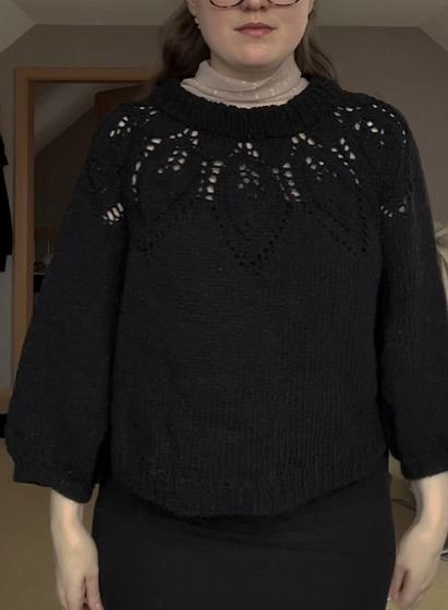 a wider perspective of the photo to showcase the length of the sweater that ends roughly mid hip and three-quarter sleeves