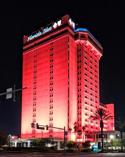 The very tall "Florida Blue" building is illuminated with red lights against a dark black, night sky.
