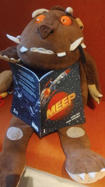 Cuddly Grufffalo plush sitting with a copy of the picture book Meep, in the children's room of the Edinburgh Bookshop
