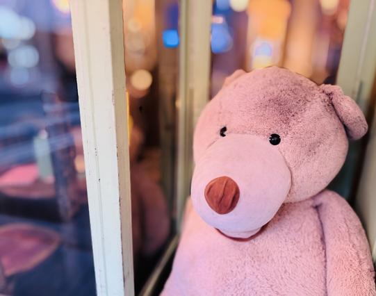 A giant teddy bear, sitting outside of a Parisian bar