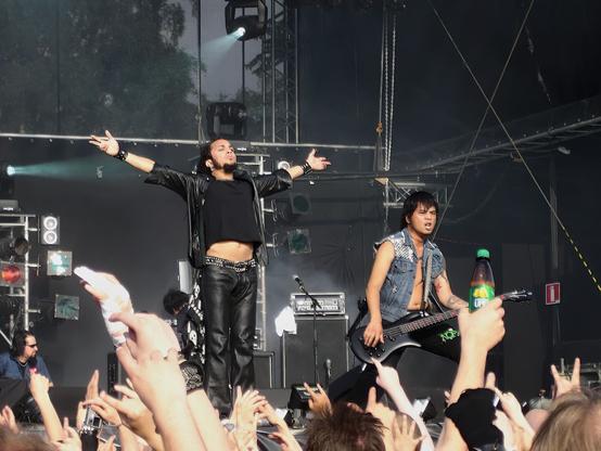 Death Angel esiintymässä Tuskan päälavalla 2004. Laulaja Mark Osegueda on levittänyt kätensä sivulle mikrofonin takana. Vierellä basisti Dennis Pepa. Kuvan alalaidassa paljon käsiä ylhäällä.