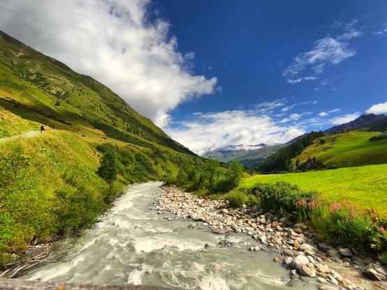 A small, but wild river flows through the valley while the sun is shining.