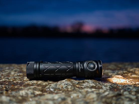 A Skilhunt EC200S flashlight with a lake in the background