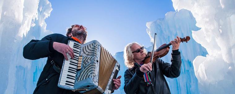 Two men play piano accordion and fiddle from the bottom of an icy crevasse