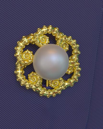3D rendering of a large pearl brooch surrounded by gold tentacles, pinned to a suit lapel of striped blue cloth.