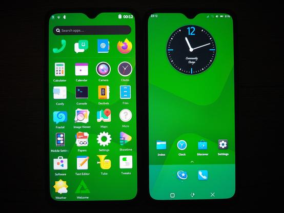 A photo of to smartphones on a desk. They are both displaying a homescreen with a green background and various app icons and widgets. On the left is Phosh, with many icons and a search bar up top. On the right is Plasma Mobile, with fewer icons and a large analog clock widget, known from the Plasma Desktop.